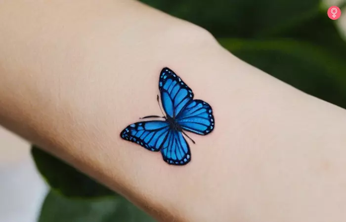 Small blue butterfly tattoo on a woman’s wrist