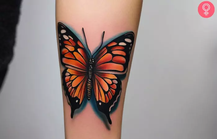 A woman wearing a butterfly tattoo on her forearm