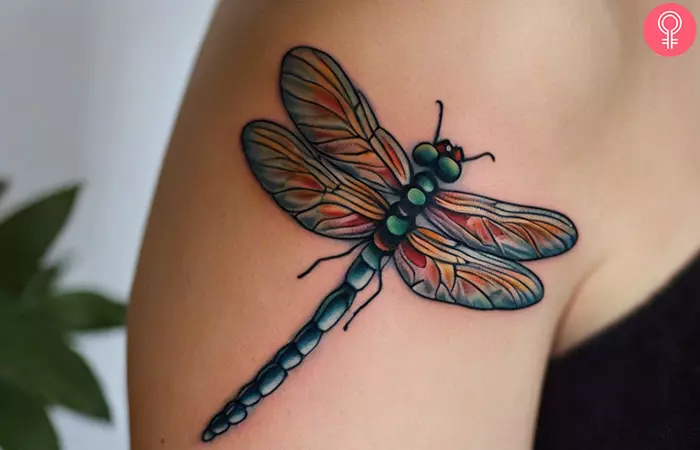 A woman wearing a dragonfly tattoo on her upper arm