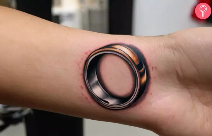 A woman wearing a 3D wedding ring tattoo on her wrist