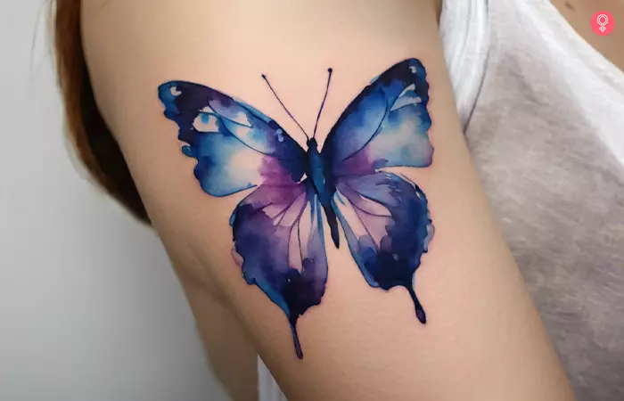 Blue and purple butterfly tattoo on a woman’s upper arm
