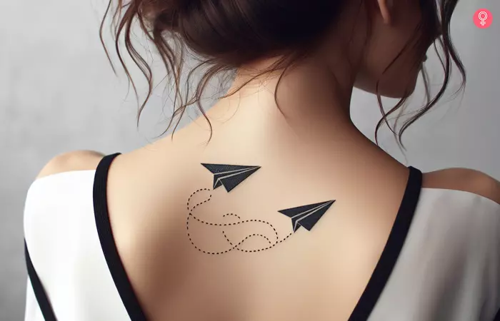 A woman with a back tattoo of two paper airplanes flying