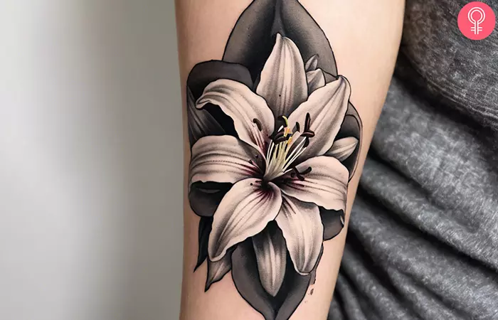 A Stargazer black and gray lily tattoo on the forearm