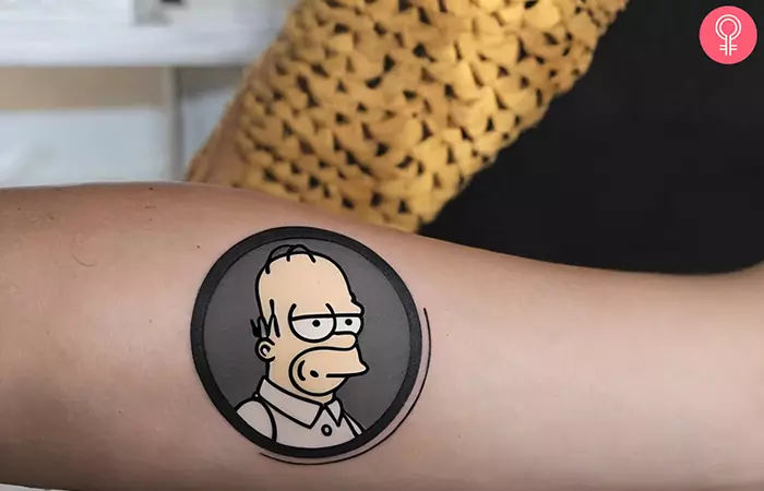 A beige, gray, and black Simpsons tattoo on a woman’s arm