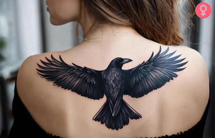 A big flying raven bird tattoo on the upper back