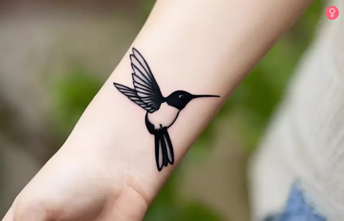 A black and white hummingbird tattoo on the wrist