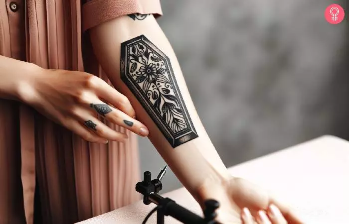 A black coffin tattoo on the forearm
