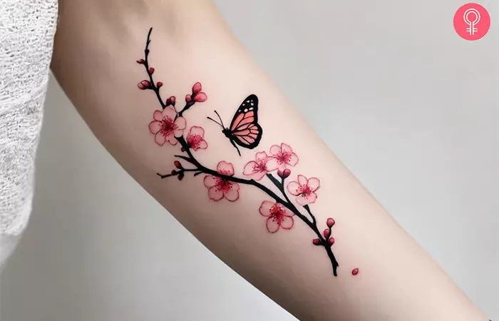 A cherry blossom tattoo with a butterfly on the forearm