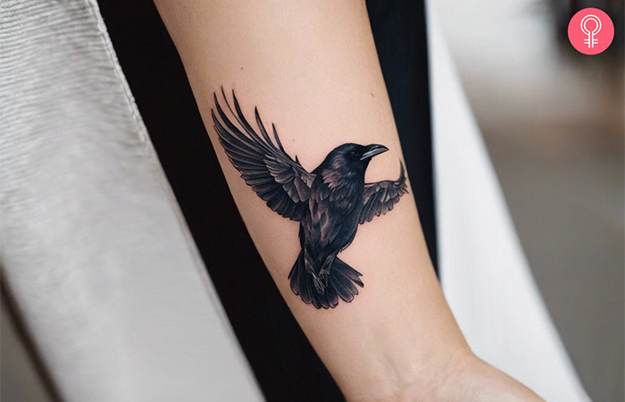 A flying raven bird tattoo on the forearm