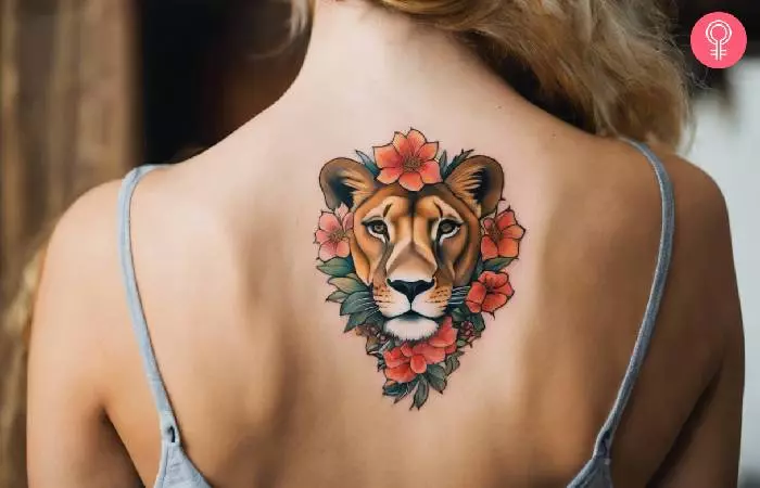 A lioness tattoo with flowers on the upper spine