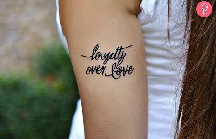 A loyalty over love tattoo on a woman’s upper arm