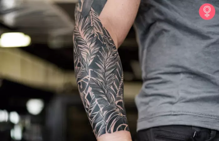 A man wearing a black and gray, jungle sleeve tattoo