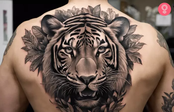 A man with a black and white jungle tattoo on the upper back