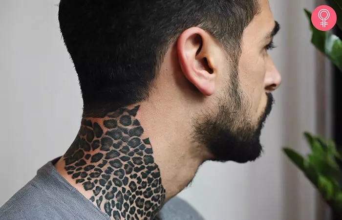 A man with a black leopard print tattoo design on his neck