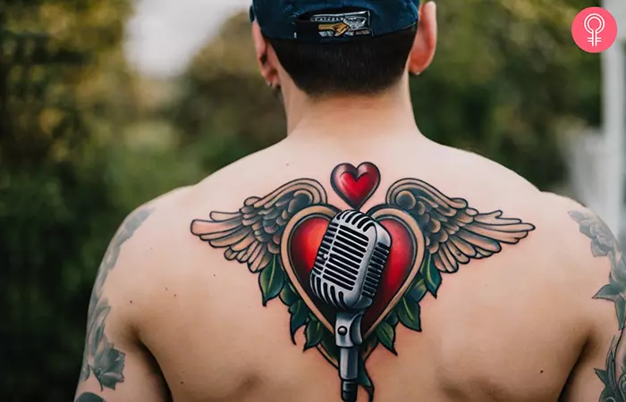 A man with a microphone, hearts, and wings tattooed on his back
