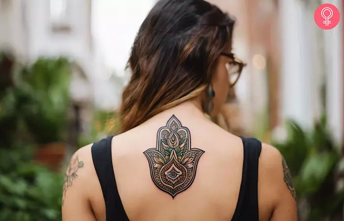 A neo-traditional hamsa hand tattoo on the upper back