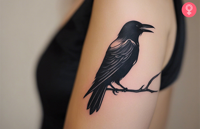 A simple raven tattoo on the arm of a woman