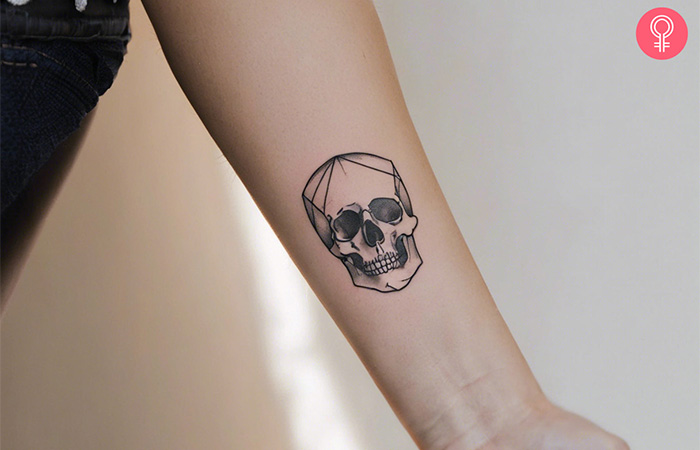 A simple skull memento mori tattoo on a woman’s forearm