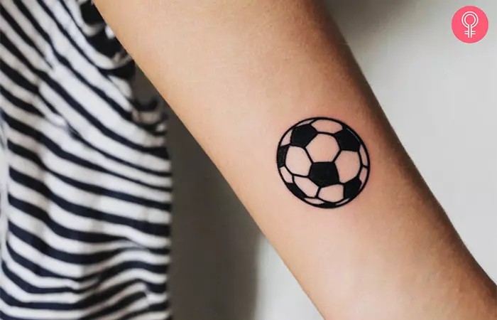 A small soccer tattoo on the wrist of a woman