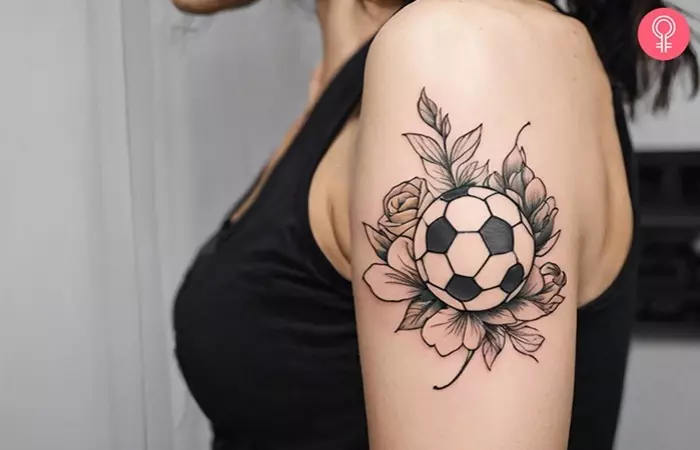 A soccer ball with flowers tattooed on the upper arm of a woman