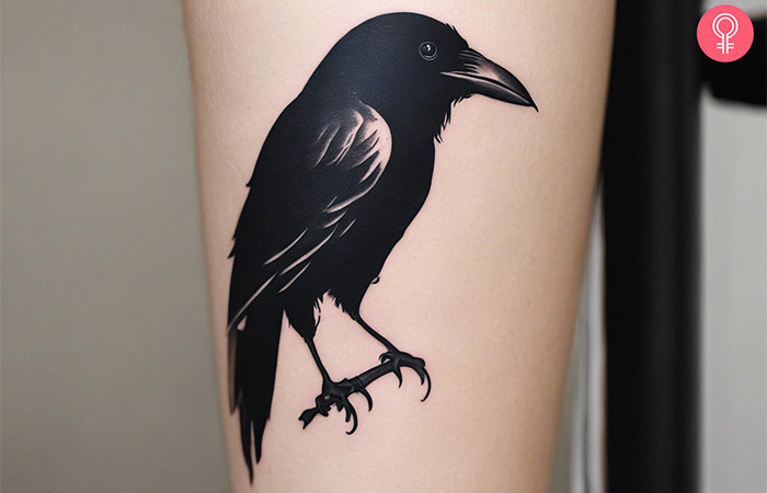 A solid black raven bird tattoo on the arm