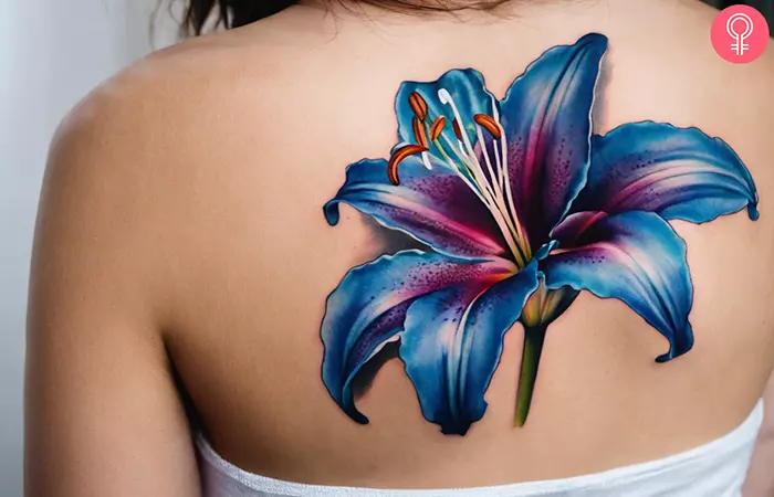 A stargazer blue and purple lily tattoo on the upper back