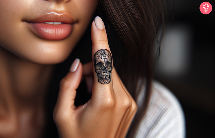 A sugar skull memento mori tattoo flaunted on a woman’s finger