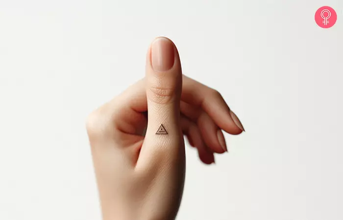 A tiny triangle tattoo on the thumb