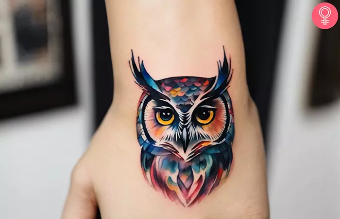 A watercolor owl tattoo on a woman’s hand