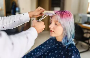 A woman getting new bangs styled at a salon