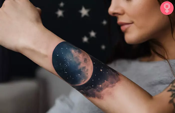 A woman showing a moon night sky tattoo on her forearm