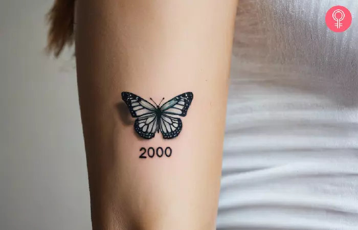 A woman with a 2000 and butterfly tattoo on her arm