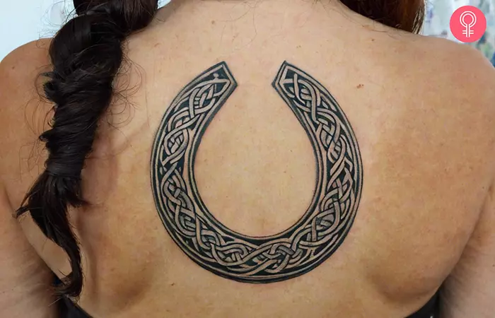 A woman with a Celtic horseshoe tattoo on her back