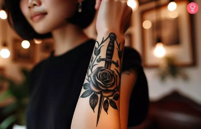 A woman with a black and gray rose and dagger tattoo