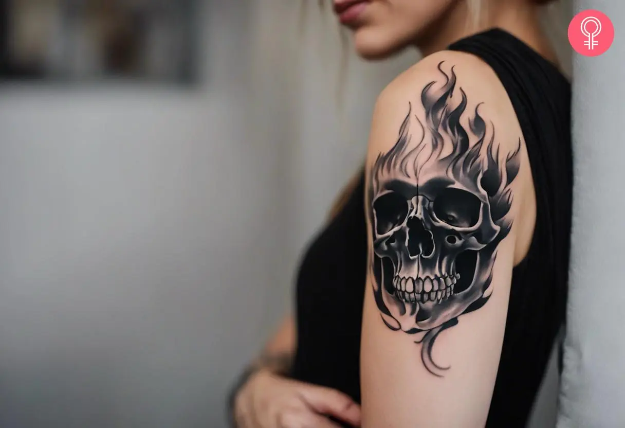 A woman with a black-and-white flame skull tattoo on her upper arm