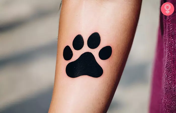 A woman with a black dog paw tattoo on forearm