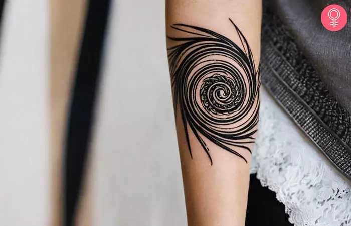 A woman with a black tribal spiral spikes tattoo on her forearm