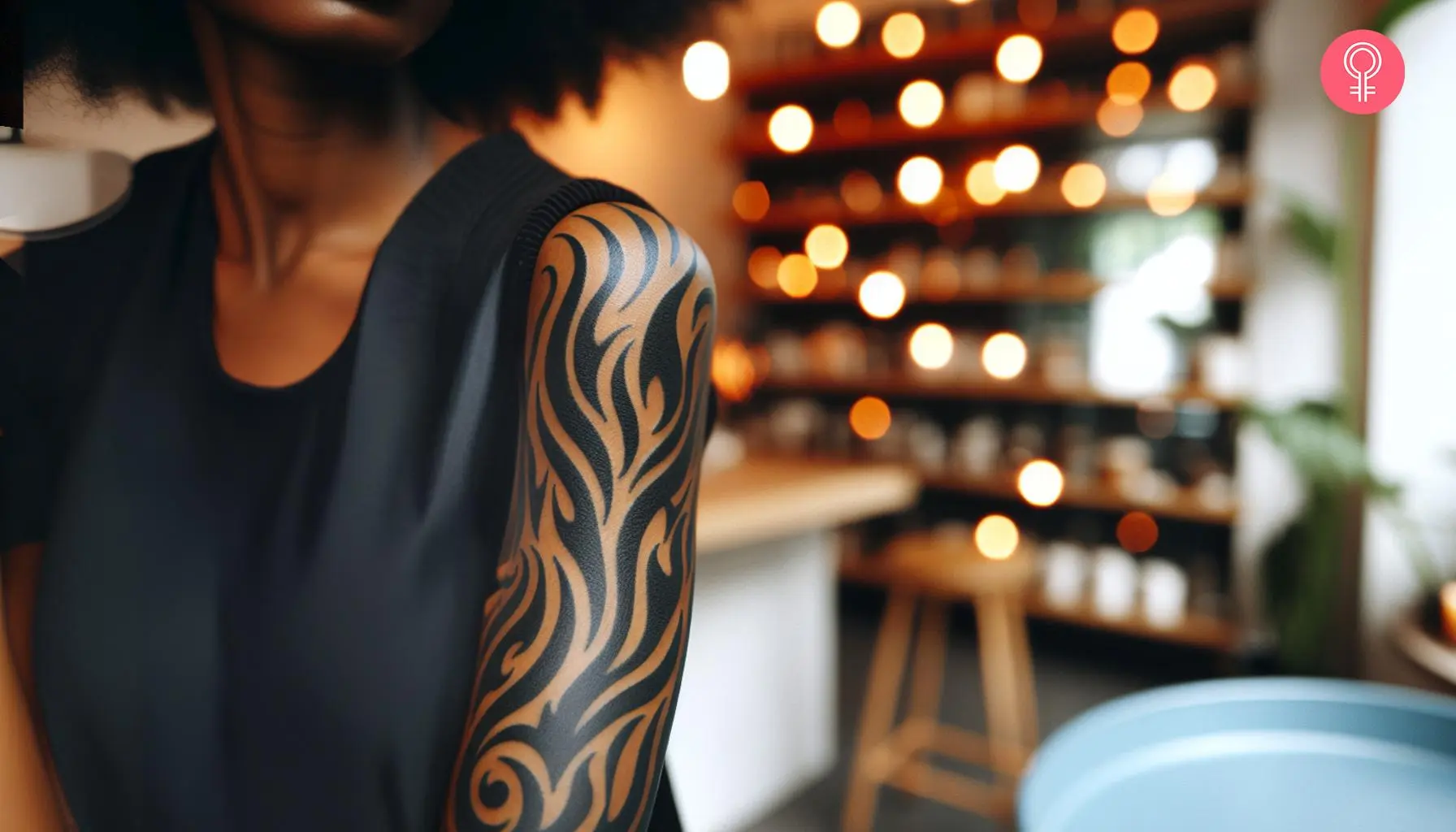 A woman with a black, tribal-style flame tattoo on her upper arm