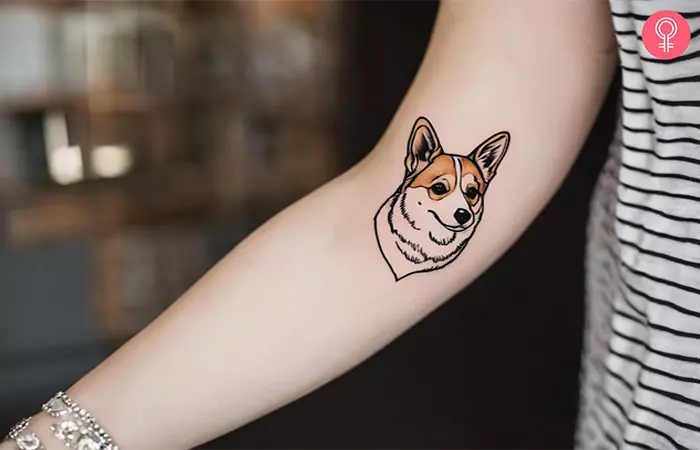 A woman with a cute, minimalist corgi tattoo on her arm