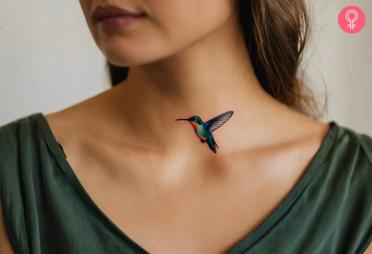 A woman with a dainty hummingbird tattoo above the collarbone