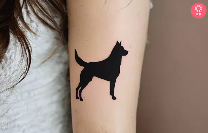 A woman with a dog silhouette tattoo on upper arm