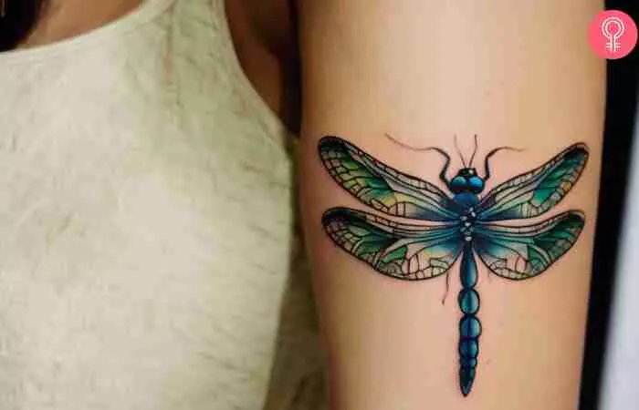 A woman with a dragonfly tattoo on her upper arm