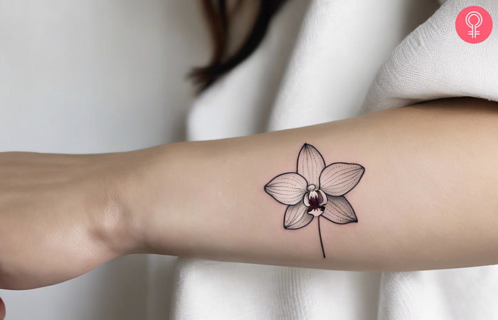 A woman with a fine line orchid tattoo on her wrist