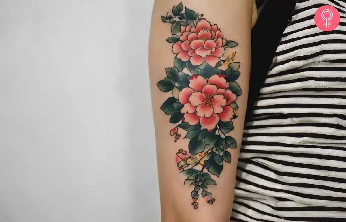 A woman with a floral Tebori tattoo design on the back of her upper arm.