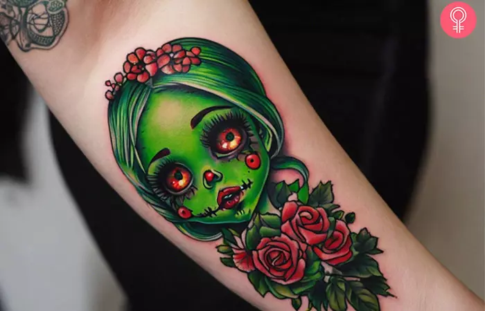 A woman with a green-hued zombie doll tattoo on her arm