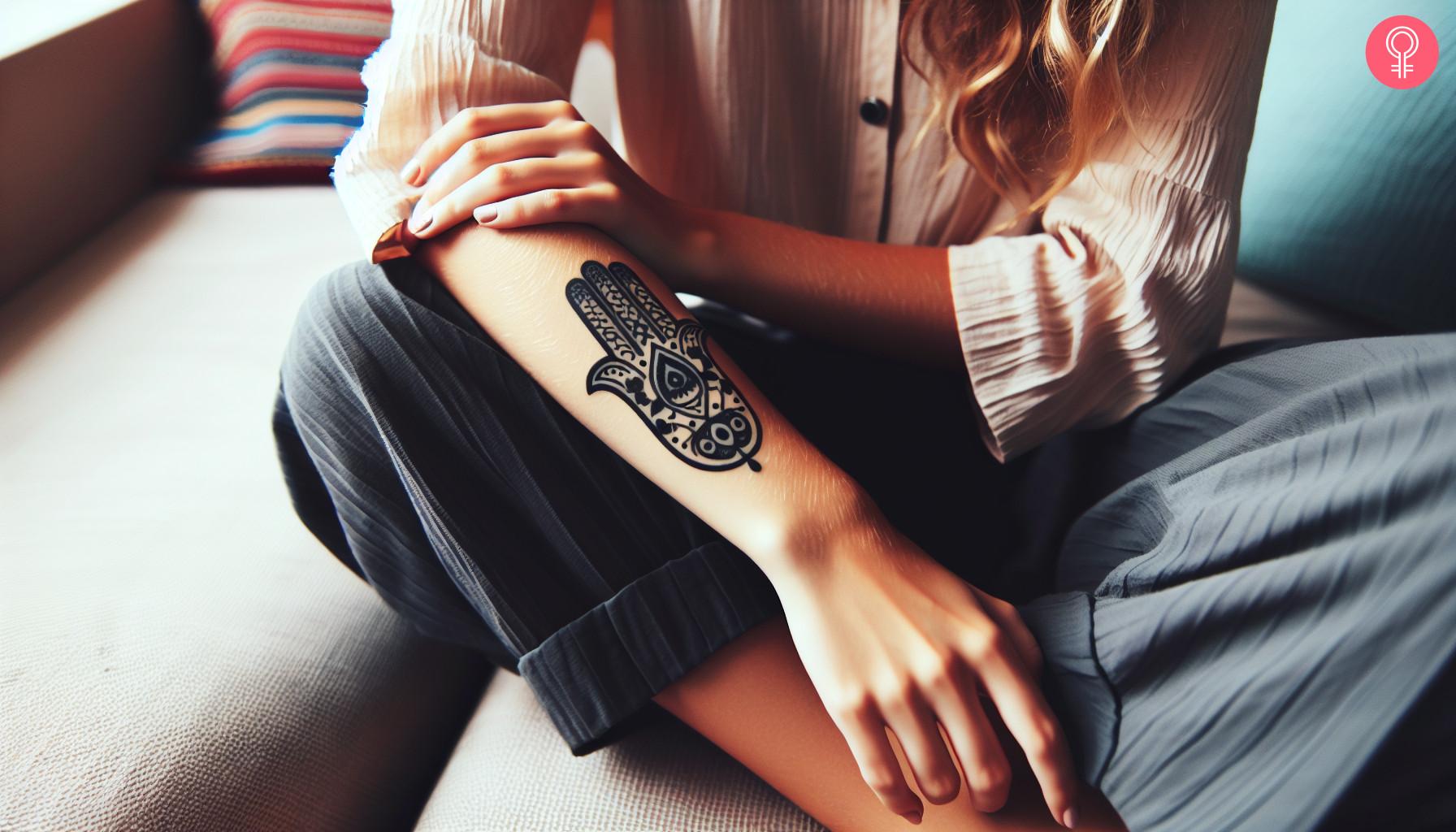 Een vrouw met een hand van hamsa-tatoeage op haar onderarm