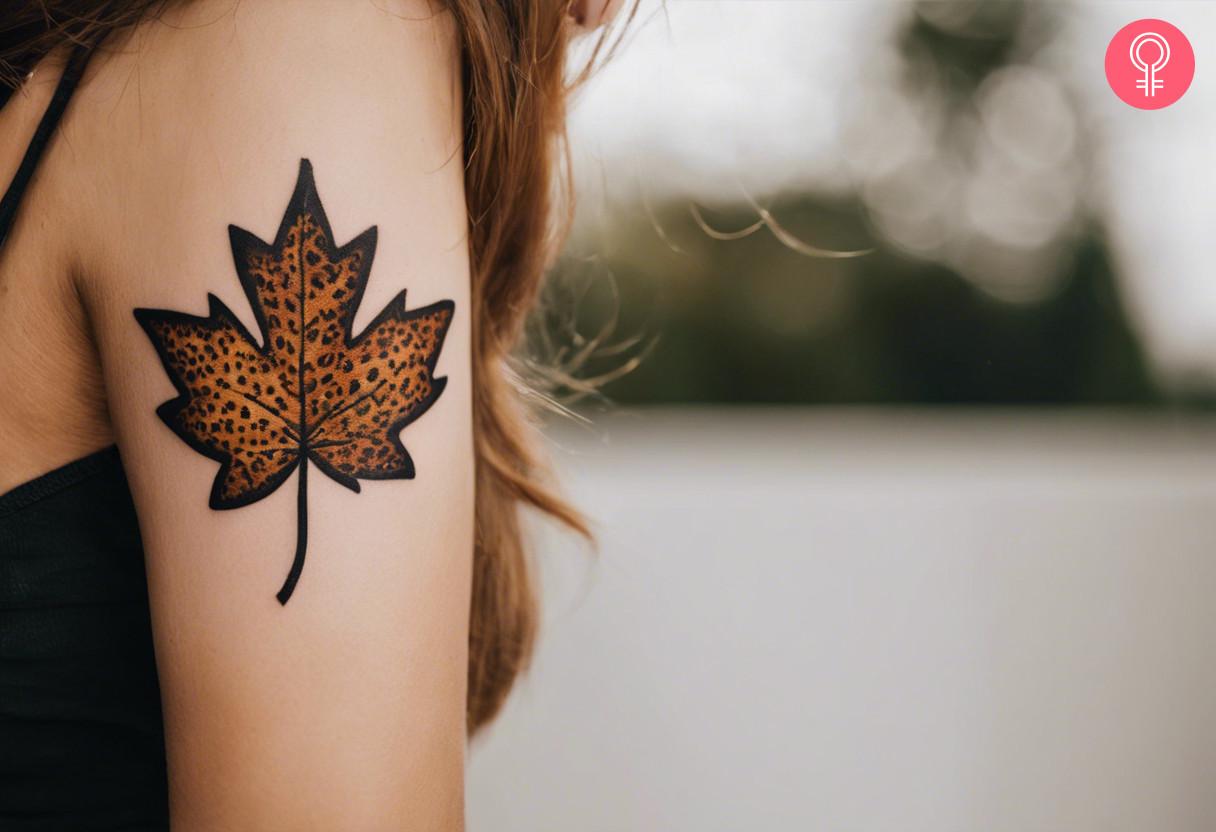 A woman with a leopard print maple leaf tattoo on her back arm