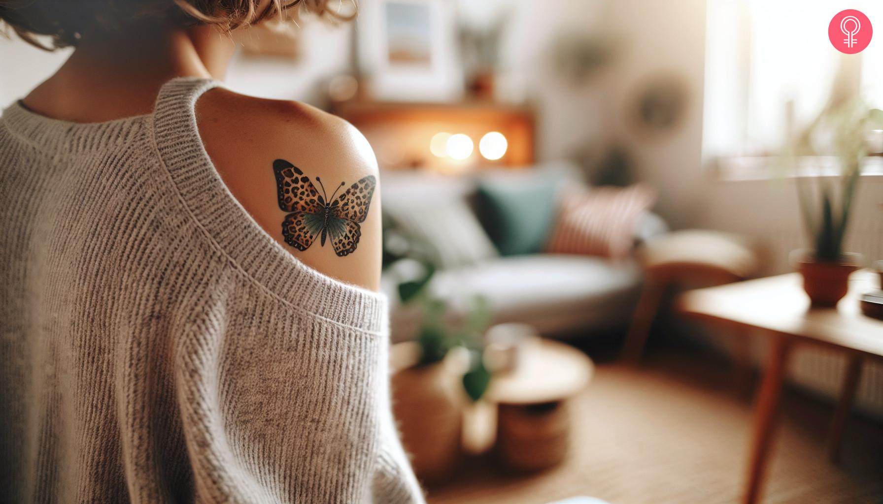 A woman with a leopard print butterfly tattoo on her shoulder