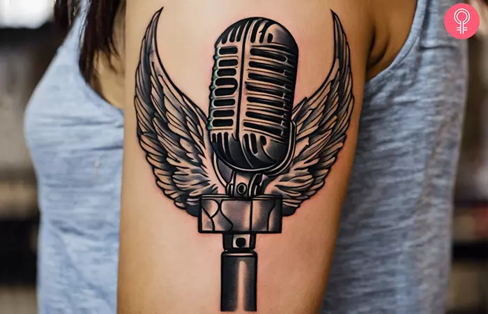 A woman with a microphone with an angel wings tattoo