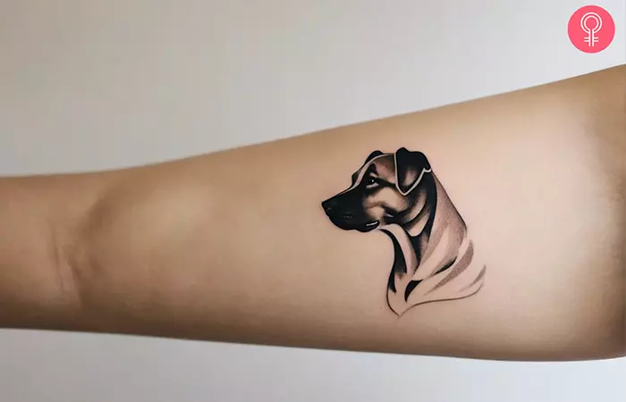 A woman with a minimalist dog portrait tattoo on forearm